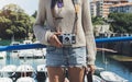 Tourist traveler photographer making pictures sea scape on vintage photo camera on background yacht and boat piar, hipster girl Royalty Free Stock Photo