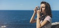 Tourist traveler photographer making pictures sea scape on vintage photo camera on background yacht and boat piar, hipster girl Royalty Free Stock Photo
