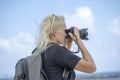 Tourist traveler photographer taking pictures of landscape on photo camera , hipster girl with backpack enjoying beautiful sea Royalty Free Stock Photo