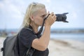 Tourist traveler photographer taking pictures of landscape on photo camera , hipster girl with backpack enjoying beautiful sea Royalty Free Stock Photo