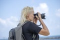 Tourist traveler photographer taking pictures of landscape on photo camera , hipster girl with backpack enjoying beautiful sea Royalty Free Stock Photo