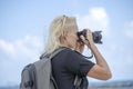 Tourist traveler photographer taking pictures of landscape on photo camera , hipster girl with backpack enjoying beautiful sea Royalty Free Stock Photo