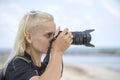 Tourist traveler photographer taking pictures of landscape on photo camera , hipster girl with backpack enjoying beautiful sea Royalty Free Stock Photo