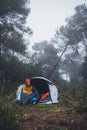 Tourist traveler ralaxing in camp tent in froggy rain forest, closeup lonely hiker woman enjoy mist nature trip, green trekking Royalty Free Stock Photo