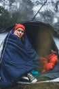 Tourist traveler ralaxing in camp tent in froggy rain forest, closeup lonely hiker woman enjoy mist nature trip, green trekking