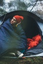 Tourist traveler ralaxing in camp tent in froggy rain forest, lonely hiker woman enjoy mist nature trip, green trekking tourism