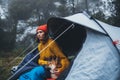 Tourist traveler relaxation red shiba inu in camp tent on background blue foggy forest, hiker woman with puppy in mist nature trip Royalty Free Stock Photo