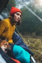 Tourist traveler relaxation red shiba inu in camp tent on background blue froggy forest, hiker woman with puppy in mist nature Royalty Free Stock Photo