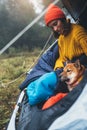 Tourist traveler relaxation red shiba inu in camp tent on background blue froggy forest, hiker woman with puppy in mist nature Royalty Free Stock Photo
