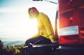 Tourist traveler traveling in car on green top on mountain, young girl smiles happily against background sunset in the mountains h Royalty Free Stock Photo