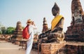 Tourist traveler woman with a backpack taking a photo of Seated Buddha Statue at Wat Ratchaburana or Wat Ratburana Buddhist temple