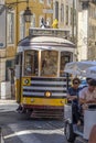 Tourist tuk tuk or three-wheeled Autorickshaw packed with tourists going up a cobblestone street in the Alfama neighborhood of