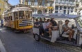 Tourist tuk tuk or three-wheeled Autorickshaw packed with tourists going up a cobblestone street in the Alfama neighborhood of