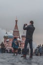 A tourist uses his smartphone to take a picture of famous St. Basil`s Cathedral at Red Square in Moscow, Russia