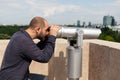 Tourist using panoramic binoculars telescope looking at metropolitan urban city Royalty Free Stock Photo