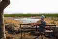 Tourist waits for wildlife at the Moringa waterhole near Halali, Etosha, Namibia