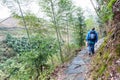 tourist walk at wet path on slope of green hill