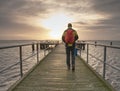 Tourist walk on wooden pier to the sea. Wooden bridge pier