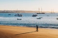 Tourist walking on the beach in Cascais, Portugal at sunrise