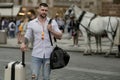 Tourist walking on city street. Traveler with suitcase. Handsome young man on business trip walking with his luggage on Royalty Free Stock Photo