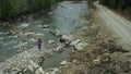 Tourist walking rocky river drone view at cloudy cold day having fun mountains