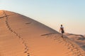 Tourist walking on the sand dunes at Sossusvlei, Namib desert, Namib Naukluft National Park, Namibia. Traveling people, adventure