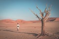 Tourist walking on the scenic desert at Sossusvlei, Namib Naukluft National Park, Namibia. Braided Acacia tree and red sand Royalty Free Stock Photo