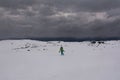 Tourist walking on a snowy plain against strong wind