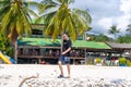 A tourist walks along a sandy tropical beach. Typical vacationer