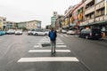 Tourist walks on a crosswalk in Yehliu fisherman village downtown area with road and buildings in northern Taipei