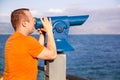 Tourist watches beautiful natural environment in telescope on beach / Panorama and view of sea and sky. Royalty Free Stock Photo