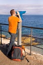 Tourist watches beautiful natural environment in telescope on beach / Panorama and view of sea and sky. Royalty Free Stock Photo