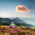 A tourist in white clothes sits on a pink carpet of rhododendron flowers Royalty Free Stock Photo