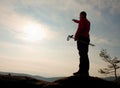 Tourist in windcheater with sporty tracking poles in hands on rocky view point