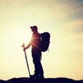 Tourist in windcheater with sporty trecking poles in hands stand on rocky view point.