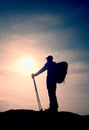 Tourist in windcheater with sporty trecking poles in hands stand on rocky view point.