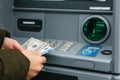 A young woman takes money from an ATM.