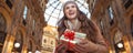 Tourist woman with Christmas gift in Milan looking into distance