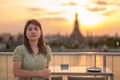 tourist woman enjoys view to Wat Arun Temple in sunset, Traveler visits Temple of Dawn near Chao Phraya river from rooftop bar. Royalty Free Stock Photo