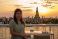 tourist woman enjoys view to Wat Arun Temple in sunset, Traveler visits Temple of Dawn near Chao Phraya river from rooftop bar. Royalty Free Stock Photo