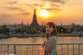 tourist woman enjoys view to Wat Arun Temple in sunset, Traveler visits Temple of Dawn near Chao Phraya river from rooftop bar. Royalty Free Stock Photo