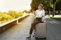 tourist woman in a European city, tourism in Europe. young woman sits on a large suitcase in the park with coffee in her