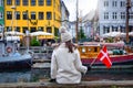 A tourist woman holding a Danish flag enjoys the view of the Nyhavn area in Copenhagen Royalty Free Stock Photo