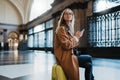 Tourist woman holding mobile phone on train platform station in Barcelona. Girl traveler waiting train holiday vacation