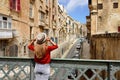 Tourist woman holds hat on iron bridge looking the old town of Valletta, Malta Royalty Free Stock Photo