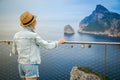 Tourist woman in jeans outfit and a straw hat looking at the Cap de Formentor