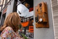 Tourist woman looking at a very old wooden phone on display on a street in Madrid, Spain. Royalty Free Stock Photo