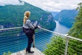 Tourist woman looks at Geirangerfjord and Seven Sisters Waterfall near small village of Geiranger. View from Eagles Road viewpoint Royalty Free Stock Photo