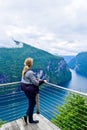 Tourist woman looks at Geirangerfjord and Seven Sisters Waterfall near small village of Geiranger. View from Eagles Road viewpoint Royalty Free Stock Photo