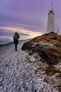 Tourist woman with photographer backpack doing to the lighthouse in Reykjanes Peninsula Reykjanesviti